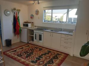 una cocina con armarios blancos y una alfombra en el suelo en Relax@99 en Featherston