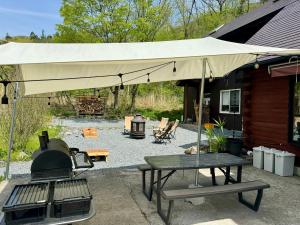 eine Terrasse mit einem Sonnenschirm, einem Grill und einem Tisch in der Unterkunft Mominoki Lodgeモミの木ロッジ in Minakami