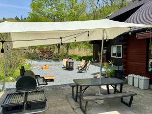 a patio with an umbrella and a grill and a table at Mominoki Lodgeモミの木ロッジ in Minakami
