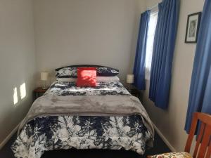 a bed with a black and white comforter and a red pillow at Relax@99 in Featherston