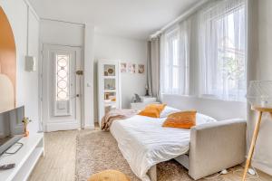 een witte slaapkamer met een bed en een stoel bij Le Sunrise Bohème - studio proche université Paris 13 in Villetaneuse