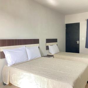 Cette chambre d'hôtel comprend 2 lits avec des oreillers blancs. dans l'établissement HOTEL TAMPICO EXPRESS MORALILLO, à Tampico