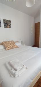 ein weißes Bett mit zwei weißen Handtüchern darauf in der Unterkunft Casa Cies in Baiona
