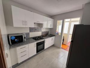 une cuisine avec des armoires blanches et un micro-ondes dans l'établissement Aida village, à Tanger