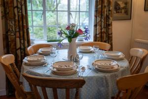 a table with plates and a vase with flowers on it at Garden Cottage in Pwllheli