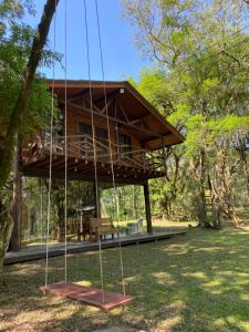 a tree house with a swing in a park at Chalé Verdant in Canoinhas