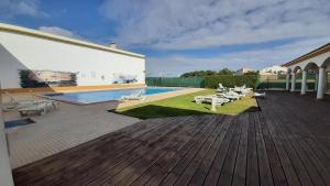 a wooden deck with a swimming pool and lounge chairs at Beach Falésia Alfamar in Albufeira