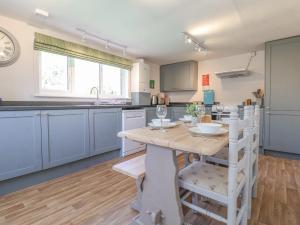 une cuisine avec des placards bleus et une table et des chaises en bois dans l'établissement 3 The Almshouse, à Saxmundham
