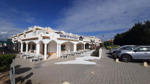 een wit gebouw met tafels en stoelen op een parkeerplaats bij Beach Falésia Alfamar in Albufeira