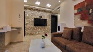 a living room with a couch and a tv on a wall at Western Gate Residence 2 Amman in Amman