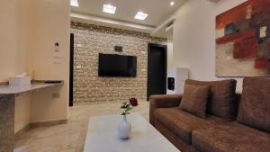 ein Wohnzimmer mit einem Sofa und einem Fernseher an der Wand in der Unterkunft Western Gate Residence 2 Amman in Amman