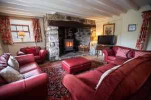 a living room with red furniture and a stone fireplace at Glasfryn Fawr in Pwllheli