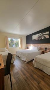 Cette chambre comprend deux lits, un bureau et une fenêtre. dans l'établissement Nova Posada, à Colonia del Sacramento
