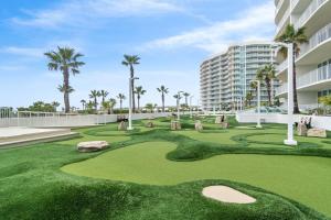 a golf course at the resort with palm trees and a building at Caribe Resort D106 by Vacation Homes Collection in Orange Beach