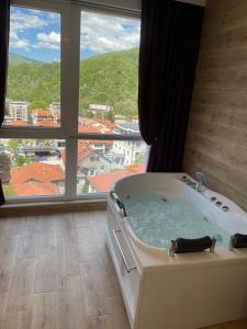 a bath tub in a room with a large window at Apartmani Vidikovac in Prijepolje