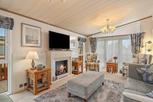 a living room with a fireplace and a tv at Cormorant - Luxury Lodge Close to the Beach in Tenby