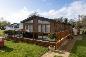 a large wooden house with a large deck at Cormorant - Luxury Lodge Close to the Beach in Tenby
