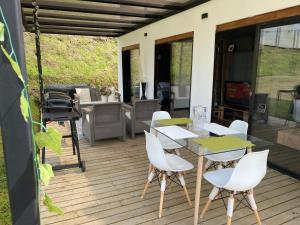 une terrasse avec des chaises blanches, une table et un grill dans l'établissement Casa campestre descanso relajación jacuzzi BBQ amplias zonas verdes, à Carmen de Viboral