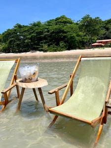 two chairs and a table in the water at Casa Tuco - Cumuruxatiba in Cumuruxatiba