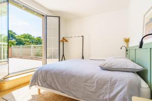 ein Schlafzimmer mit einem Bett und einem großen Fenster in der Unterkunft La Conciergerie Biarritz in Biarritz