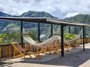 - un ensemble de chaises et de hamacs sous un toit dans l'établissement Hotel Pueblo del mundo, à Baños