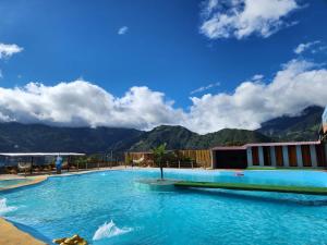 une grande piscine avec des montagnes en arrière-plan dans l'établissement Hotel Pueblo del mundo, à Baños