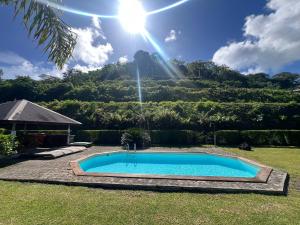 una piscina in un cortile con una montagna sullo sfondo di Bungalow Tipanier - Vue parfaite a Tevaitoa