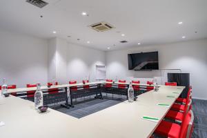 una sala de conferencias con una mesa larga y sillas rojas en Ibis Styles Invercargill, en Invercargill