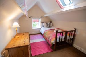 a small attic bedroom with a bed and a table at Rose Cottage in Pwllheli