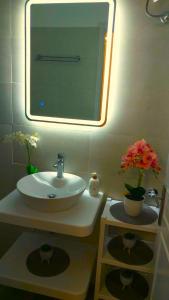baño con lavabo, espejo y flores en Panayota Apartments, en Kassiopi
