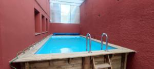 a swimming pool in a room with a red wall at Estudio completo familiar in La Jonquera