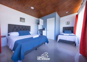 a bedroom with two beds with blue and white sheets at Canto Del Bosque in San Vito