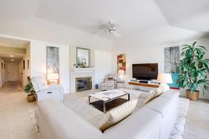 sala de estar con muebles blancos y TV de pantalla plana en Sunny Palm Springs Haven Fenced Patio, 6 Pools!, en Palm Springs