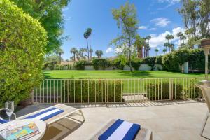 a patio with two lounge chairs and a fence at Sunny Palm Springs Haven Fenced Patio, 6 Pools! in Palm Springs