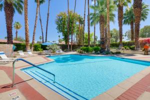 a swimming pool with palm trees in a resort at Sunny Palm Springs Haven Fenced Patio, 6 Pools! in Palm Springs