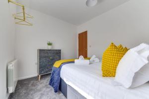 a bedroom with a large white bed with yellow pillows at Exquisite 1st Floor Apartment in Sheffield