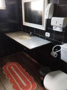 een badkamer met een wastafel, een toilet en een spiegel bij Praia da Cocanha - Caraguá SP - Área gourmet TOP in Caraguatatuba