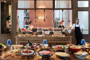 a chef standing in a kitchen with a buffet of food at Artizan - Design Hotel in Tbilisi City