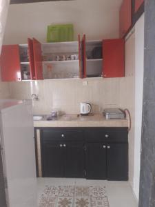 uma cozinha com armários vermelhos e uma bancada em منزل الضيافة em Rabat