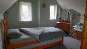 a bedroom with a bed and a dresser and two windows at Merrilees B&B in Holland-on-Sea