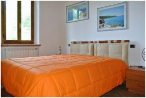 un letto arancione in una camera bianca con finestre di “Il Nespolino” Tuscan Country House a Siena