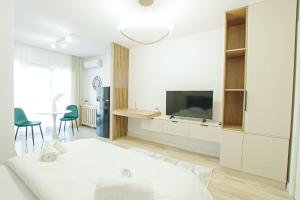 a white living room with a white bed and a tv at Himson Stylish Studio-Self Check-in near Airport & Mall in Iaşi