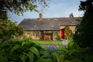 una vieja casa de piedra con una puerta roja y flores en The Longhouse, en Pwllheli