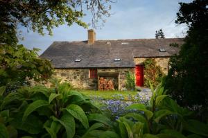 an old stone house with a red door and flowers at The Longhouse in Pwllheli