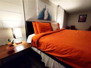 a bedroom with an orange bed and a night stand at Spacious Suite Close to Downtown Indy/ King Bed in Indianapolis