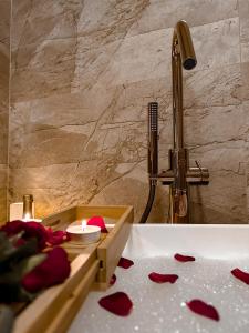 a bathroom sink with red rose petals on the floor at Apartament Perła - Zator Energylandia in Zator