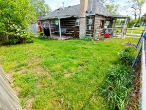 una casa vieja con un patio con una valla en Wolf's Cabin-Walk to Downtown Noblesville, en Noblesville