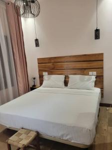 a bedroom with a large white bed with a wooden headboard at Villa Soudan in Bobo-Dioulasso