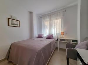 a white bedroom with a bed and a window at Apartamento Miró in Calpe