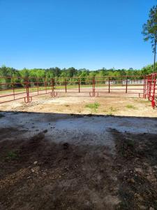 un campo di terra con una recinzione rossa sullo sfondo di Horse Hotel and Guest Cabin ad Andalusia